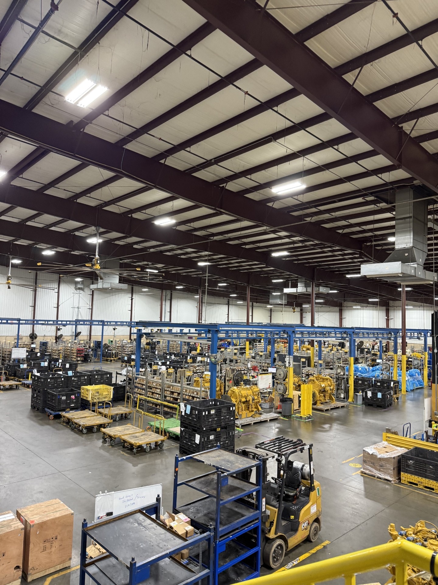 Industrial warehouse interior with high-bay LED lighting system illuminating a large manufacturing and parts distribution facility
